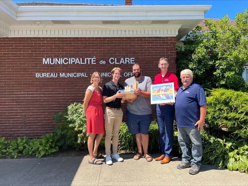 Le préfet Yvon LeBlanc, le sous-préfet Éric Pothier, la conseillère Nadine Comeau et deux représentants du Louisiana's Cajun Bayou échangent un cadeau devant le bureau municipal.